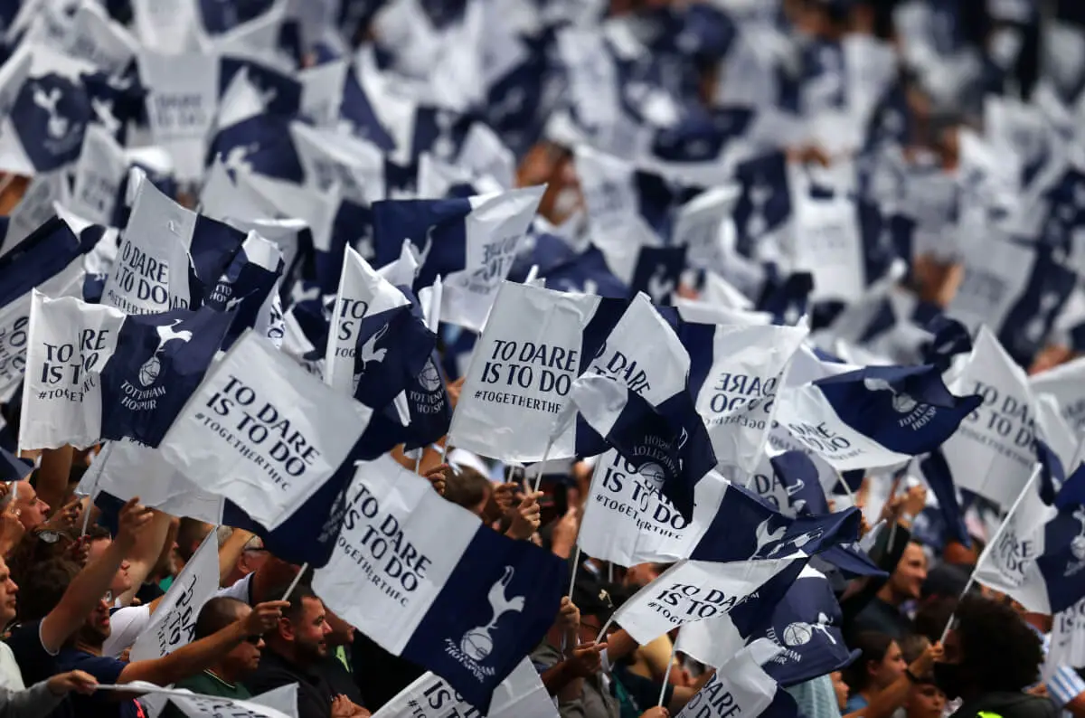 Tottenham Hotspur flags being held by supporters at the Tottenham Hotspur Stadium.