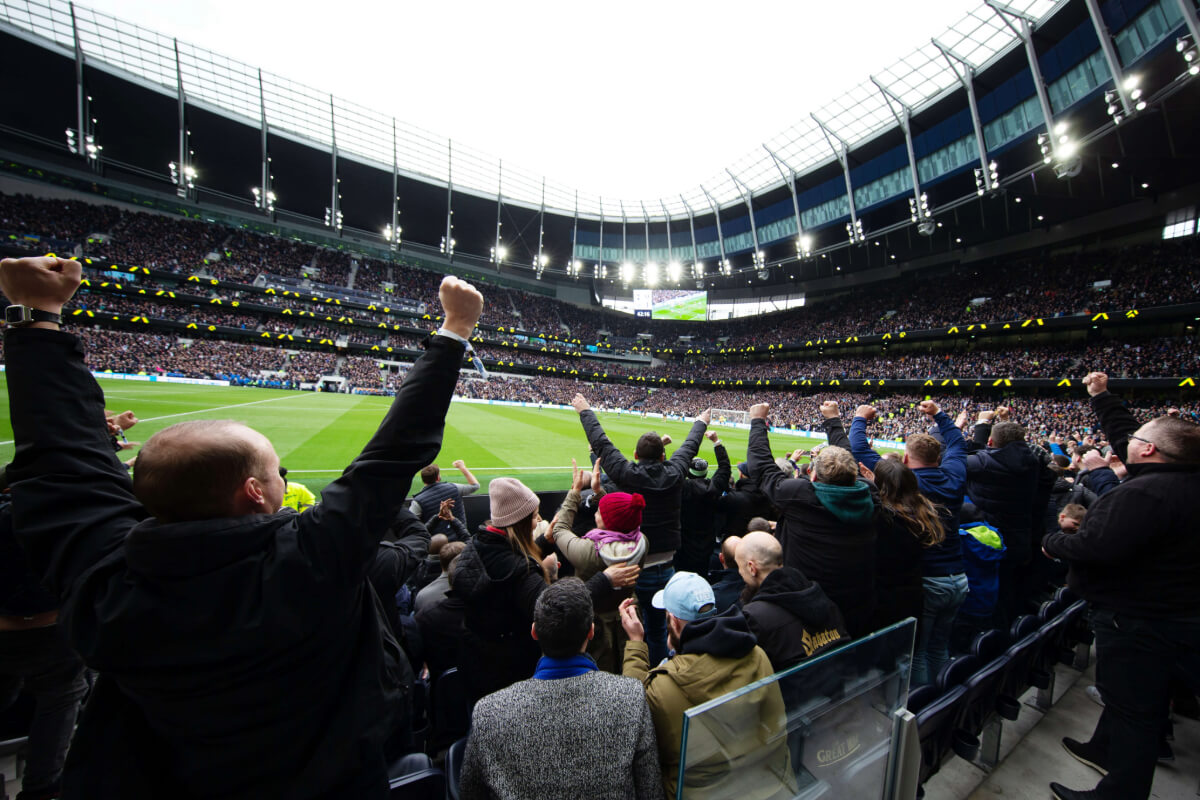 Tottenham Hotspur fans celebrating in the stands at the Tottenham Hotspur Stadium.