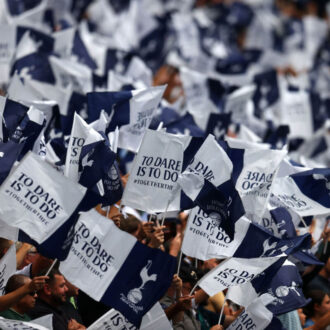 Tottenham Hotspur flags being held by supporters at the Tottenham Hotspur Stadium.