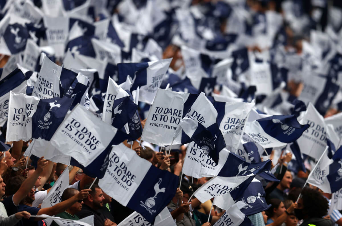 Tottenham Hotspur flags being held by supporters at the Tottenham Hotspur Stadium.