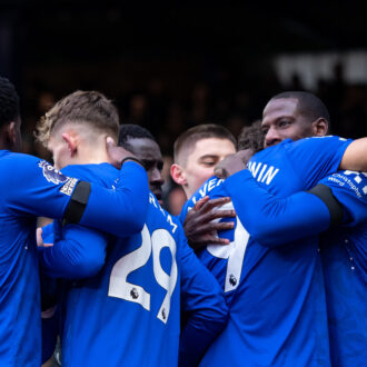 Everton players hugging and celebrating together.