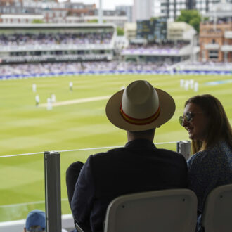 Couple enjoying the view across the wicket at Lord's Cricket Ground, London.
